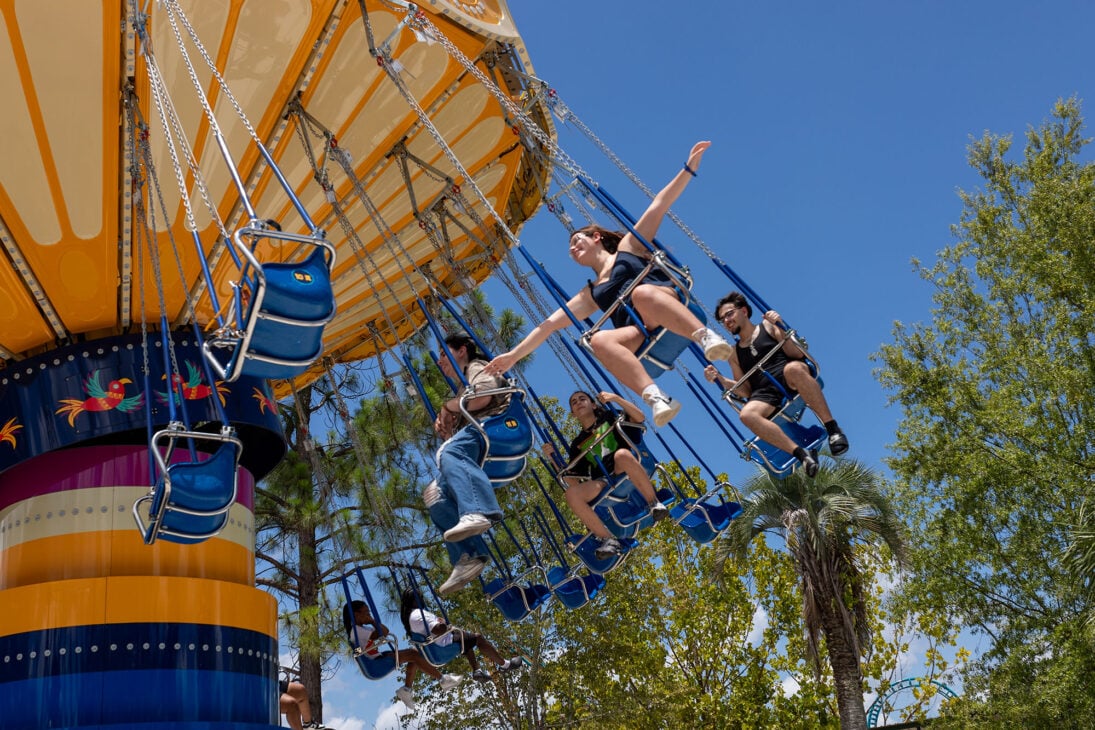 teenager on swings at a theme park with her arms out pretending to fly